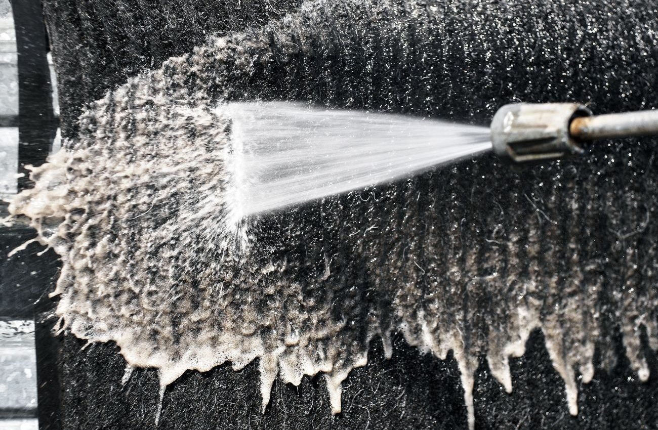 Professional Carpet Cleaning for Lasting Freshness A person operates a hose to clean a black cloth, illustrating a carpet cleaning service in Los Angeles, CA.